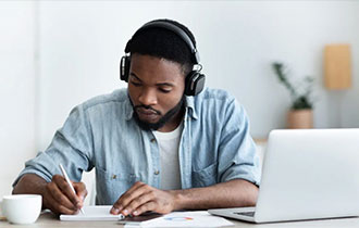 a black boy with headphone writting on a paper